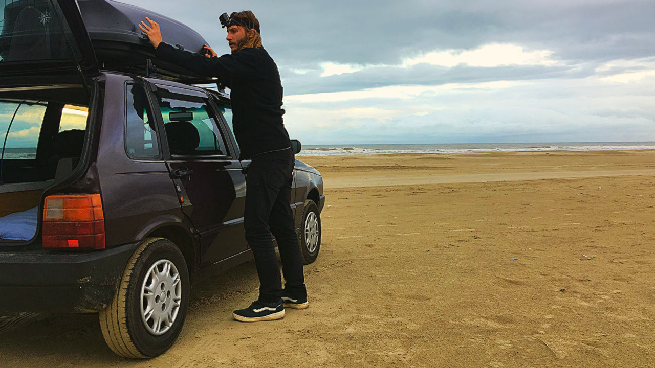 Tarcísio organizando o bagageiro do Fiat Uno motorhome em uma praia